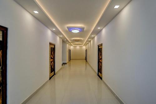 a long corridor with white walls and a ceiling with a light at Spot On THE RAJA GRAND in Akbarpur
