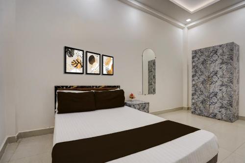 a bedroom with a bed and two pictures on the wall at Spot On THE RAJA GRAND in Akbarpur