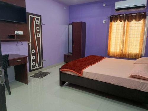 a bedroom with a bed and a desk and a television at Hotel O Shrihaan Residency in Rāmachandrapuram