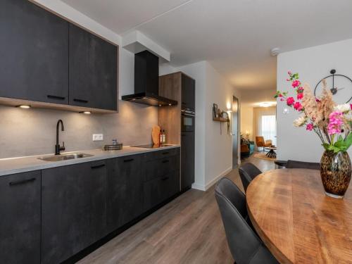a kitchen with black cabinets and a wooden table at Unique apartment, located on the Oosterschelde and marina of Sint Annaland in Sint Annaland