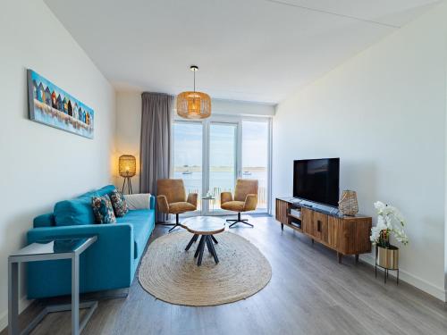 a living room with a blue couch and a tv at Unique apartment, located on the Oosterschelde and marina of Sint Annaland in Sint Annaland
