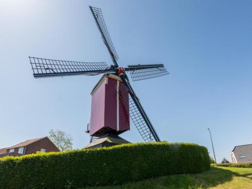 a windmill in a field with a hedge at Unique apartment, located on the Oosterschelde and marina of Sint Annaland in Sint Annaland