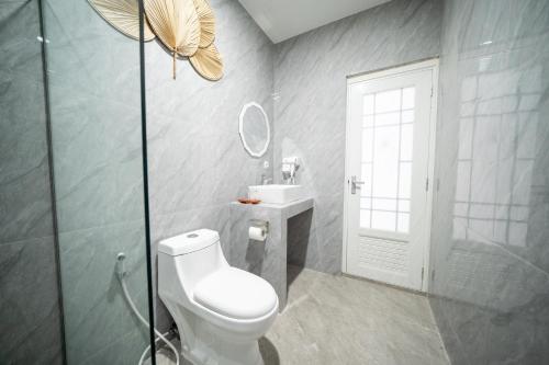 Un baño con inodoro, lavabo y espejo. en Ayodhya Villa Jogja, en Jetis