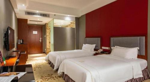 a bedroom with two beds and a red wall at Shunde Emperor Hotel in Shunde
