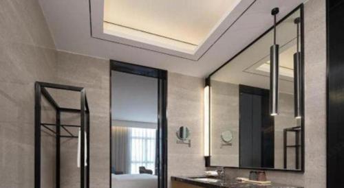 a bathroom with two mirrors and a sink and a tub at Zhuhai Tangyi Hotel in Zhuhai