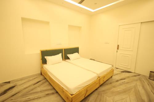 a bedroom with a bed with white sheets and a door at Shuddhi Villa by Aarogya's in Udaipur