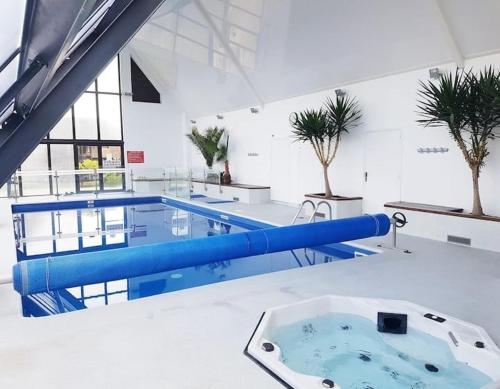 ein großes Schwimmbecken mit blauen Trennwänden in einem Gebäude in der Unterkunft Deauville Proche Plage - Piscine Chauffée - Jacuzzi - Sauna in Deauville