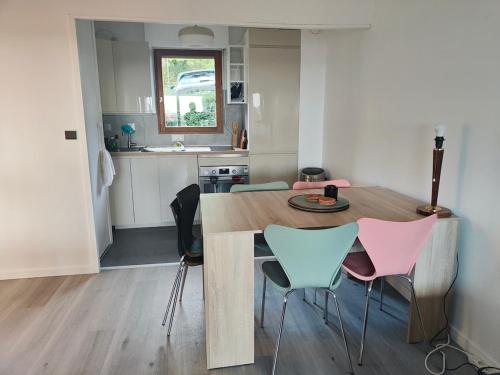 eine Küche mit einem Holztisch und rosa und blauen Stühlen in der Unterkunft Deauville Proche Plage - Piscine Chauffée - Jacuzzi - Sauna in Deauville