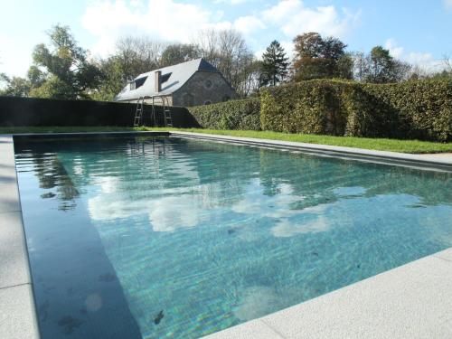 GesvesにあるBoutique Holiday Home in Gesves with Swimming Poolの家屋を背景にしたスイミングプール