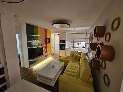 Una sala de estar con un sofá amarillo y una mesa. en Apartman ALEK Stupine ,Tuzla, en Tuzla