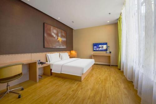 a hotel room with a bed and a desk and a computer at IU Hotel Taiyuan Changfeng West Street The Mixc in Taiyuan