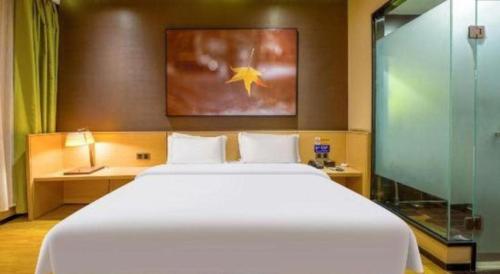 a bedroom with a large white bed and a glass shower at IU Hotel Taiyuan Changfeng West Street The Mixc in Taiyuan