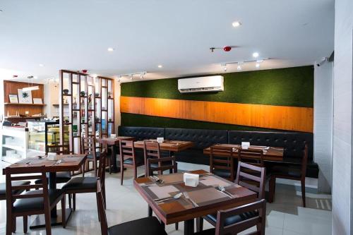 a restaurant with wooden tables and a green wall at Hotel Fleur de Liz in Panglao