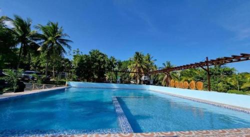 a pool in a resort with palm trees in the background at Yemaya de Laiya powered by Cocotel in Batangas City