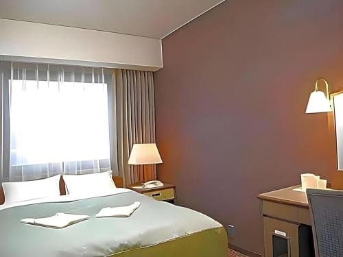 a hotel room with a bed and a window at Sunroute Aomori Hotel in Aomori