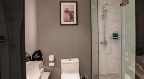 a bathroom with a white toilet and a shower at Magnotel Hotel Dongxing Guomen Port in Fangcheng