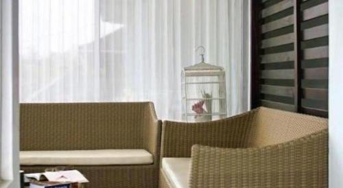 a room with two chairs and a bird cage in a window at The Studio Inn Nusa Dua in Ubud