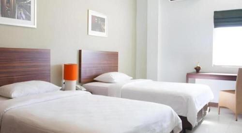 a bedroom with two beds and a chair in it at The Studio Inn Nusa Dua in Ubud