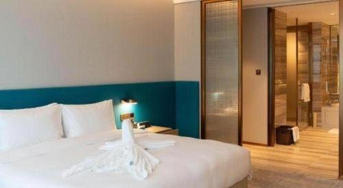 a bedroom with a white bed with a blue wall at Zhuhai Hongsanyi Hotel in Zhuhai