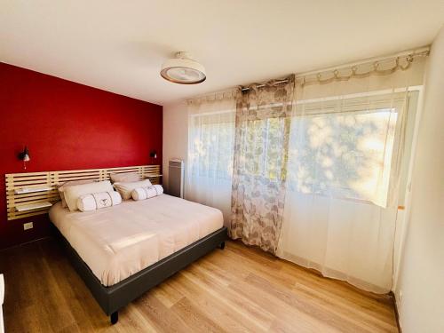 a bedroom with a bed with a red wall at T2 proche Thermes Vals Idéal curistes et familles in Vals-les-Bains