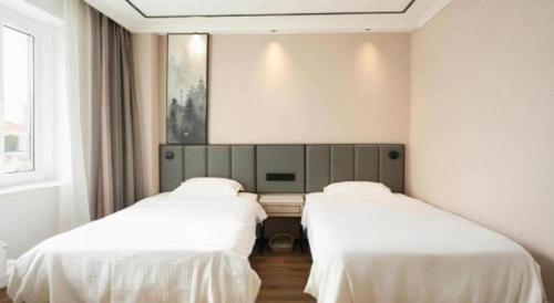 two beds in a room with white sheets at GreenTree Inn Langfang Sanhe South Yingbin Road Express Hotel in Sanhe