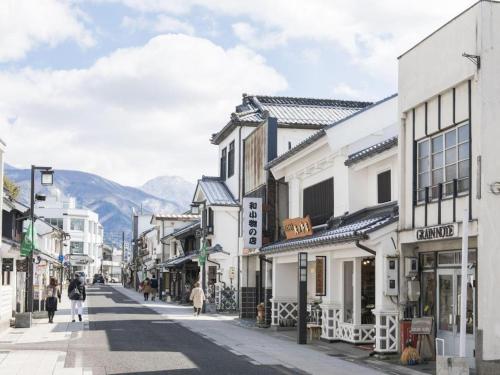 a street with buildings and people walking down a street at Premier Hotel Cabin Matsumoto in Matsumoto