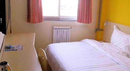 a bedroom with a white bed and a window at 7 Days Inn Baoding Railway Station in Baoding