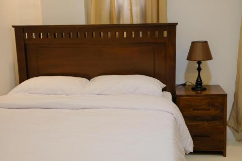 a bed with a wooden headboard and a table with a lamp at Saffire Beach Resort and Glamping in Pagudpud