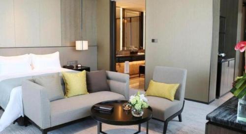 a living room with a bed and a couch and a table at Golden Eagle Summit Hotel Kunshan in Suzhou