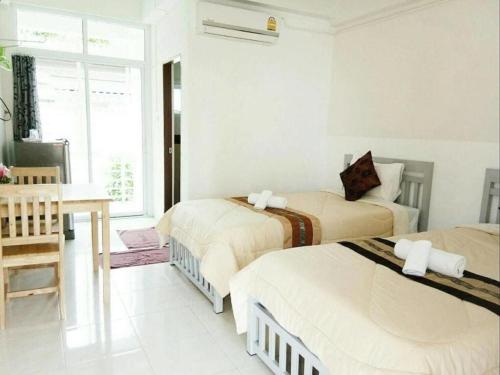 a white room with two beds and a table at Rueangrat Hotel in Ranong