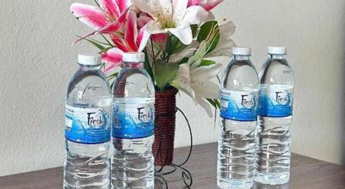 three bottles of water and a vase with flowers at Rueangrat Hotel in Ranong
