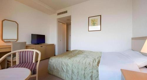 a bedroom with a bed and a desk and a tv at Grand Hotel New Oji in Tomakomai