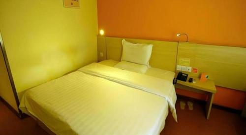 a bedroom with a large white bed and a table at 7 Days Inn Changzhou Yancheng Technology Metro Station in Changzhou
