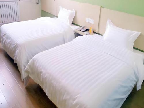 two beds in a hotel room with white sheets at 7 Days Inn Wuhan Hanyang Wanda Plaza in Wuhan