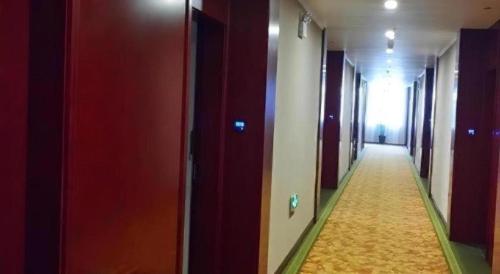 an empty corridor of a building with red doors at GreenTree Inn Xuzhou High Speed Railway Zhangqian Square Business Hotel in Xuzhou