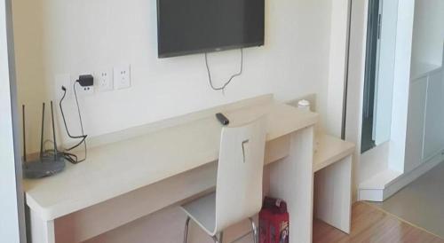 a white desk with a tv on a wall at 7 Days Inn Dongsheng Railway Station in Ordos