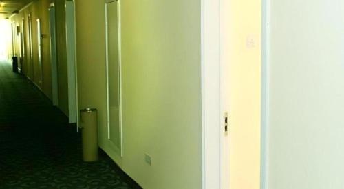 a hallway of an office with green walls and a door at 7 Days Inn Dongsheng Railway Station in Ordos