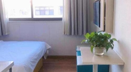 a room with a bed and a table with a potted plant at 7 Days Inn·Taixing Wenchang Road in Taixing