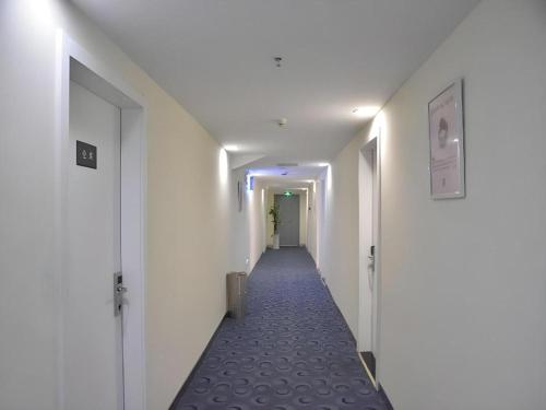a hallway with white walls and a long corridor at 7 Days Inn Yiyang Shengli Road in Shangrao