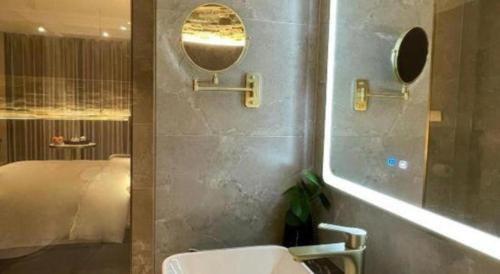 a bathroom with a sink and a mirror and a bed at Chaozhou Hotel in Chaozhou