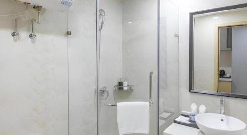 a white bathroom with a shower and a sink at Imin Hotel in Huadu