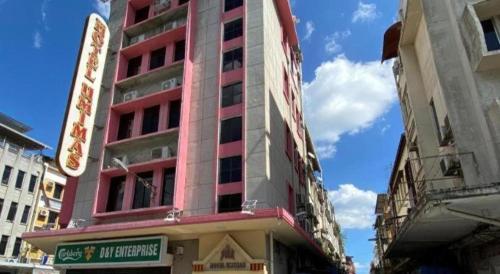 a tall pink building on a city street at OYO 89958 Hotel Umimas in Lahad Datu