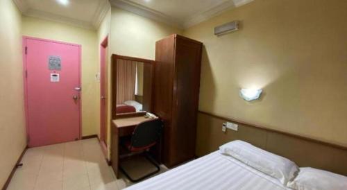a bedroom with a bed and a desk and a pink door at OYO 89958 Hotel Umimas in Lahad Datu