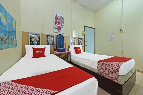 a room with two beds with red and white sheets at SPOT ON 90625 Super Green Grass Hotel in Yong Peng