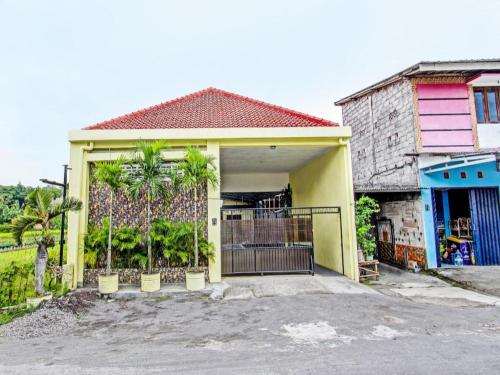 a yellow house with a gate and palm trees at OYO 91920 Pondok'ku Inn in Yogyakarta