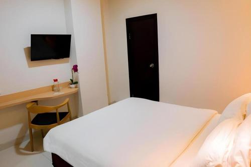 a bedroom with a bed and a desk with a television at Life Hotel Soekarno Hatta Makassar in Makassar