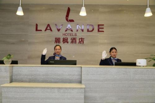 two women sitting at a counter with their hands up at Lavande Hotels Suzhou Railway Station in Suzhou