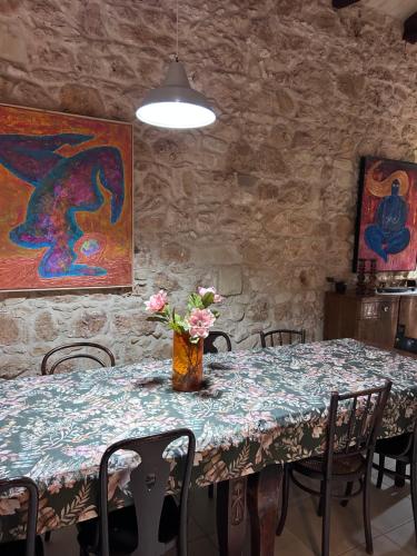 a dining room table with a vase of flowers on it at Ta Skorba Farmhouse Mgarr in Mġarr