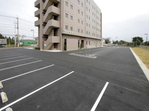 an empty parking lot in front of a building at Hotel Sunoak Kashiwanoha in Kashiwa