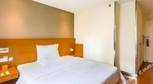 a bedroom with a large white bed with a wooden headboard at 7 Days Inn West Gate of Taiyuan University of Technology in Taiyuan